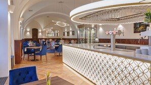Un restaurant avec un plafond haut, un éclairage moderne et un bar agrémenté d’une cloison décorative.