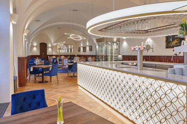 Un restaurant avec un plafond haut, un éclairage moderne et un bar agrémenté d’une cloison décorative.