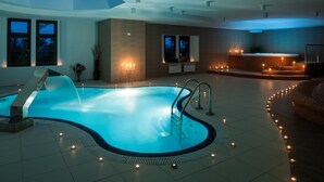 Une piscine intérieure moderne, dotée d’un système de filtration à eau claire, entourée d’un sol carrelé et agrémentée de nombreuses bougies.