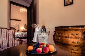 Une table à manger avec un plateau de fruits, une bouteille de champagne et un pichet en verre.