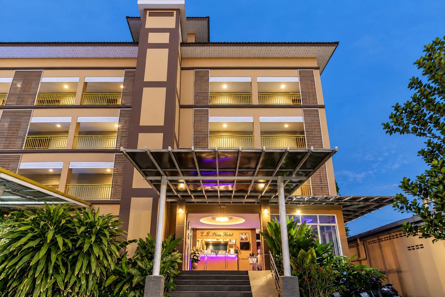 Un hotel con una fachada moderna, varios balcones y una entrada bien iluminada.