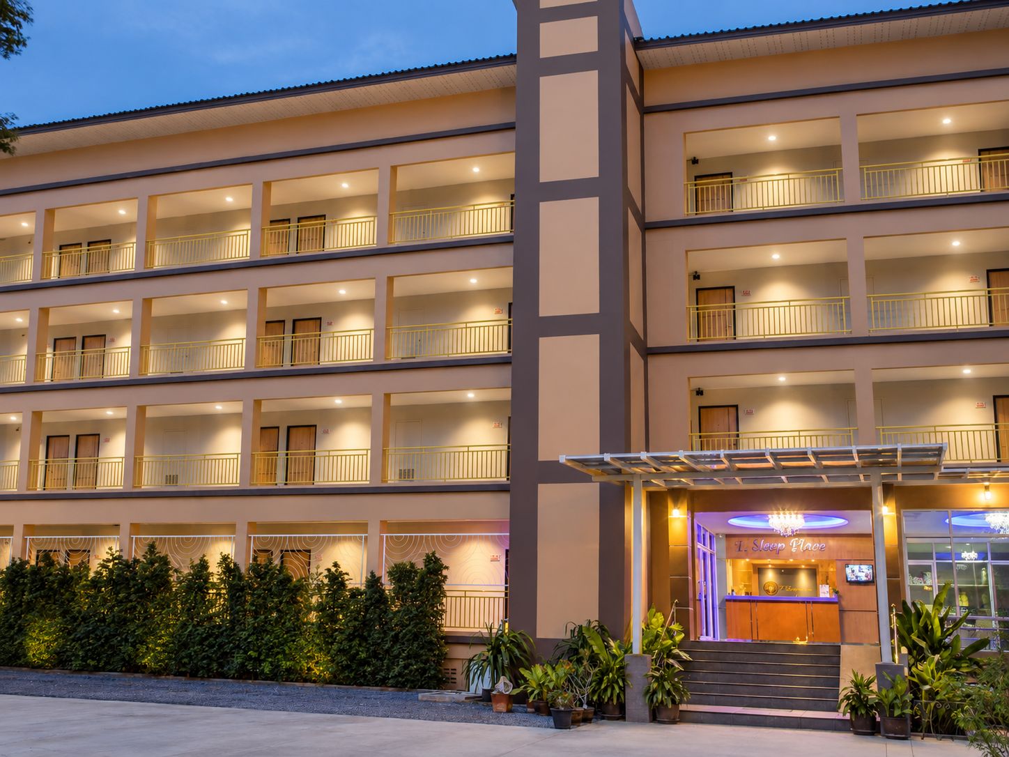 Un hotel de varios pisos con balcones, una recepción y una entrada bien iluminada.