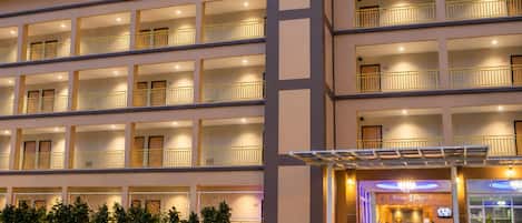 Un hotel de varios pisos con balcones, una recepción y una entrada bien iluminada.