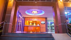 A entrada do T. Sleep Place, com uma receção, um candelabro e uma escadaria.