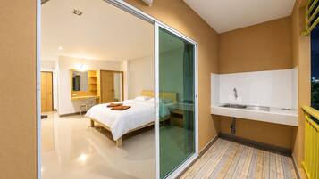 Een hotelkamer met een bed, een badkamer met een wastafel en een balkon met een hekwerk.