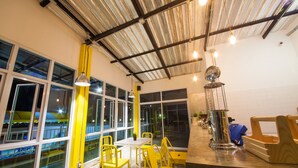 Um interior moderno com janelas amplas, cadeiras amarelas e um espaço de bar.
