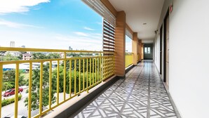 Corredor com piso estampado, corrimão amarelo e vista para a paisagem urbana.