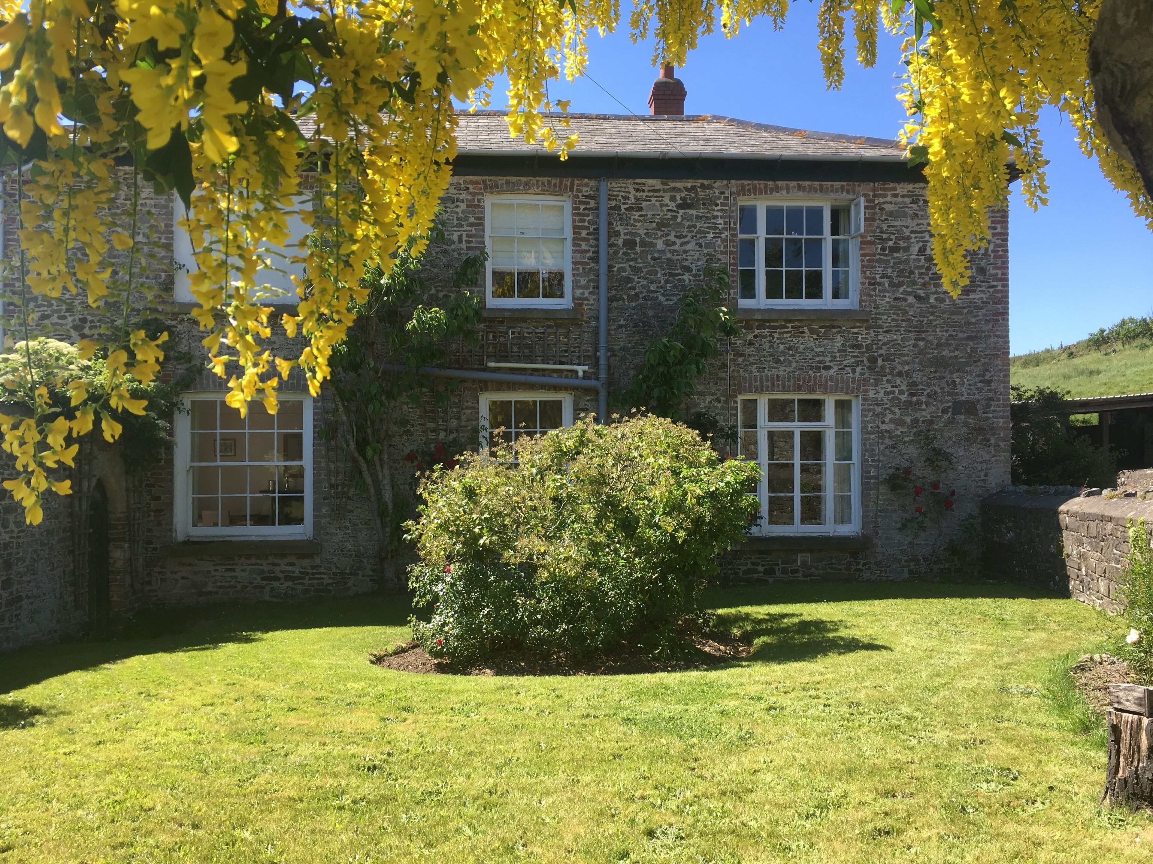 A stone building with multiple windows and a well-maintained lawn.