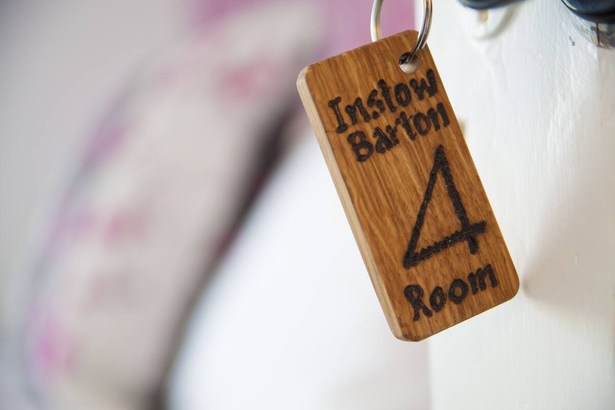 A wooden tag with "Inslow Barton 4 Room" engraved on it.