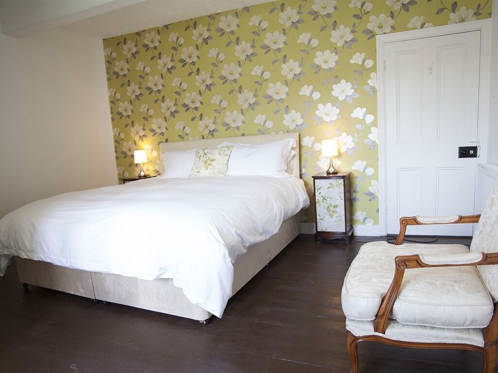 A bedroom with a bed, two bedside tables with lamps, a chair, and a door.
