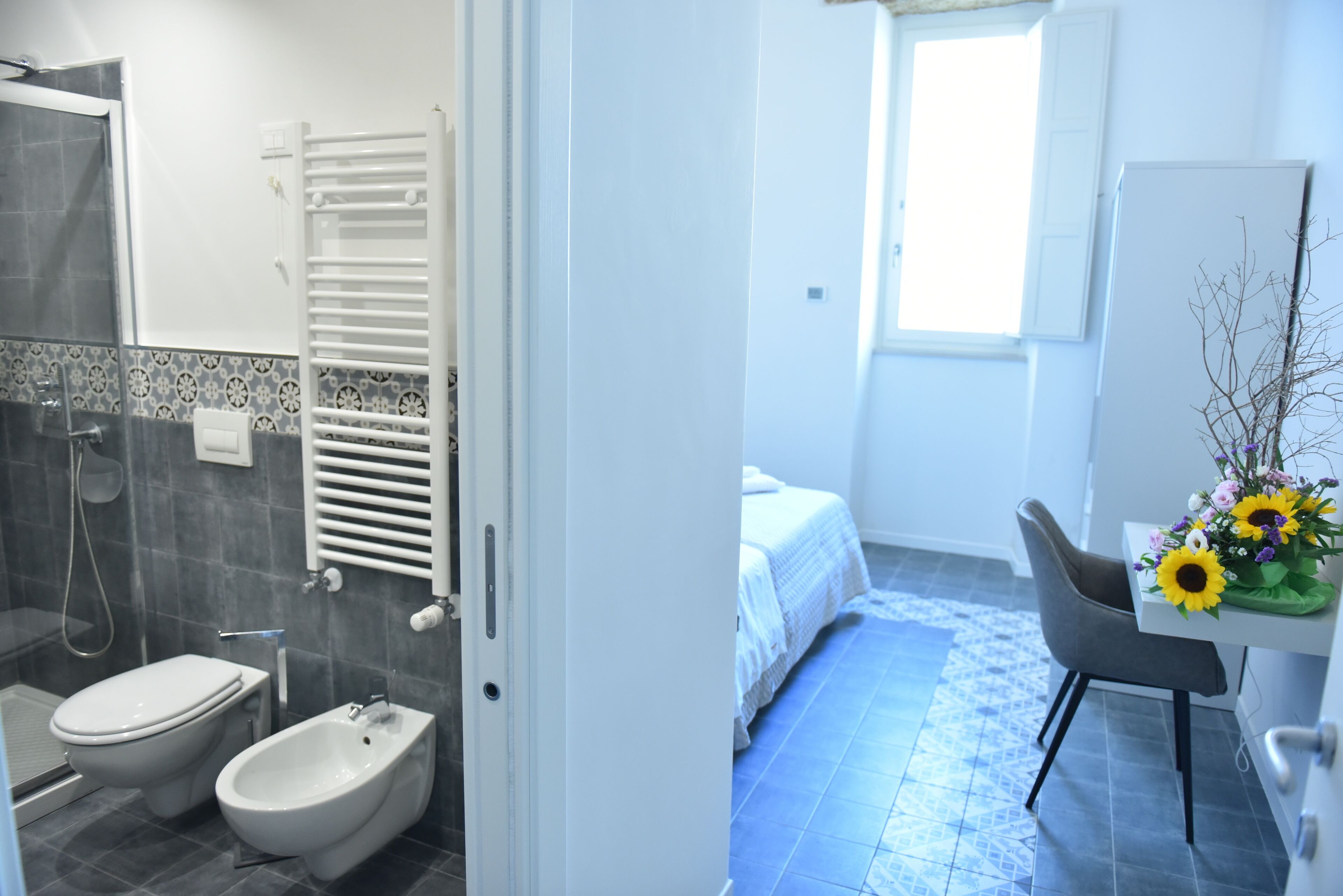 A bathroom with a shower, toilet, bidet, and a towel rack.