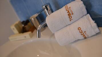 A bathroom sink with two towels labeled "TOBACCO SUITE" hanging on a rack.