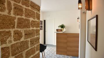 Un pasillo con pared de ladrillo, un mostrador de recepción de madera, una silla negra y baldosas de suelo estampadas.
