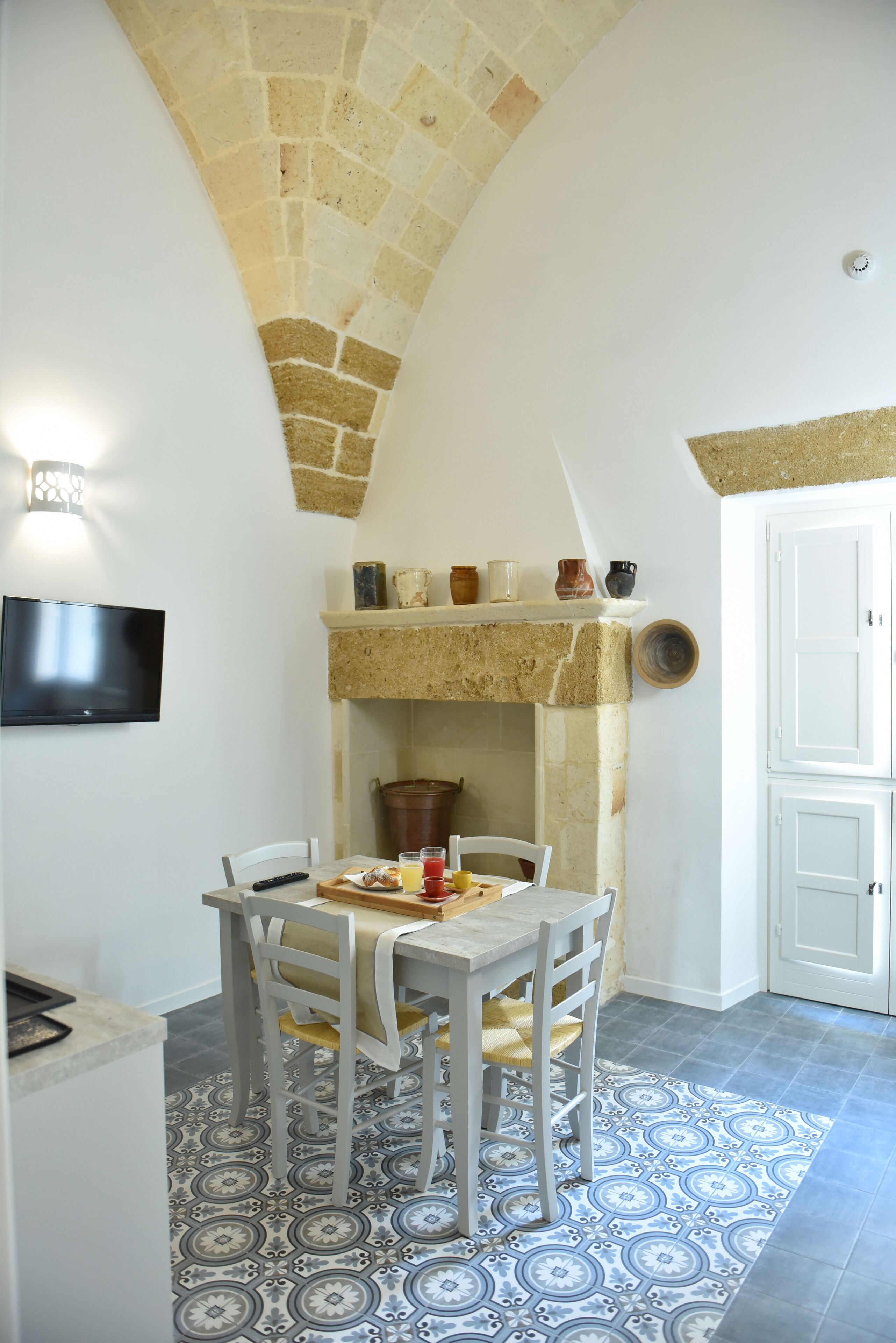 Un comedor con chimenea de piedra, un televisor montado en la pared y un suelo con diseño.