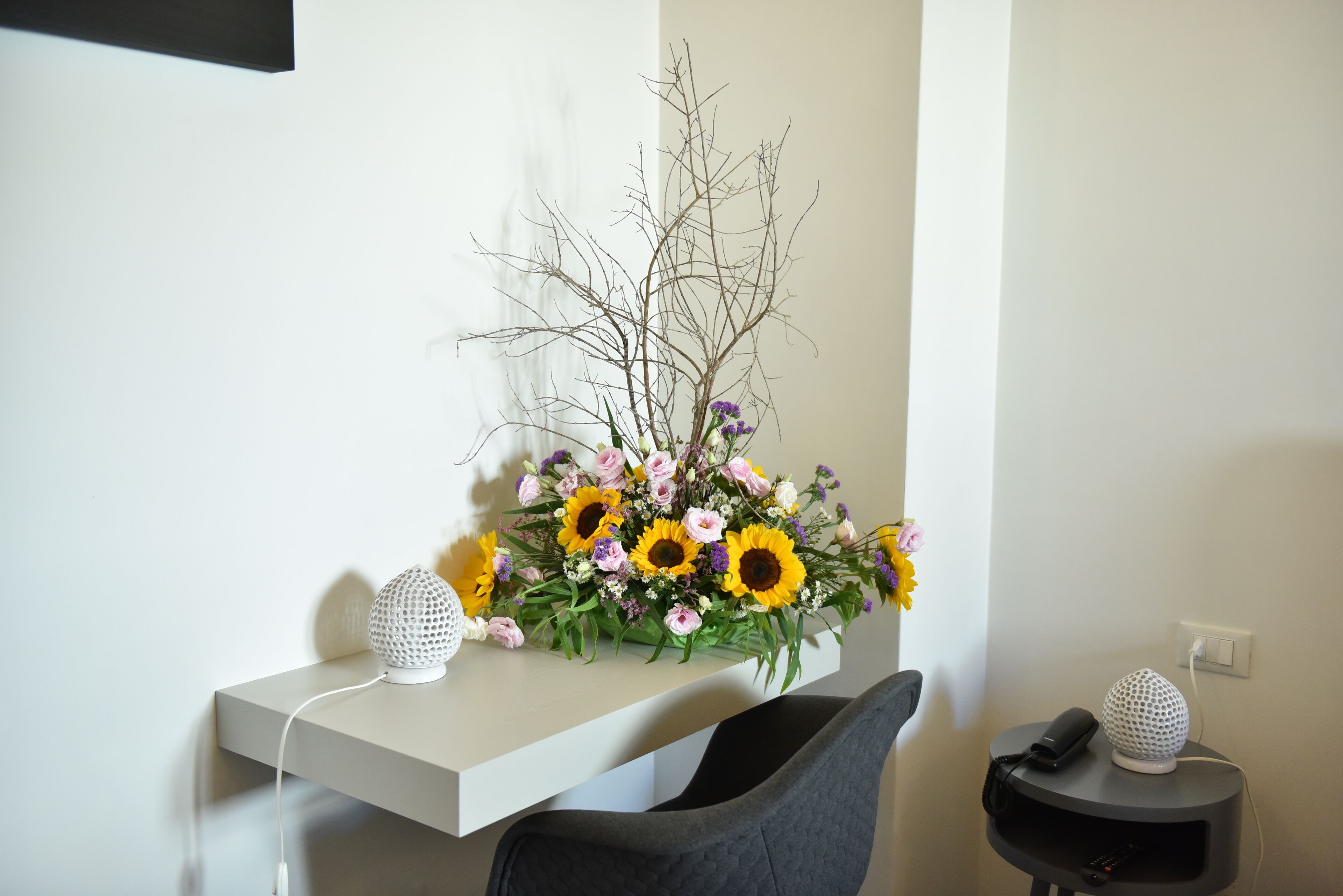 A modern room with a white desk, a grey chair, and a small table with a spherical object on it.