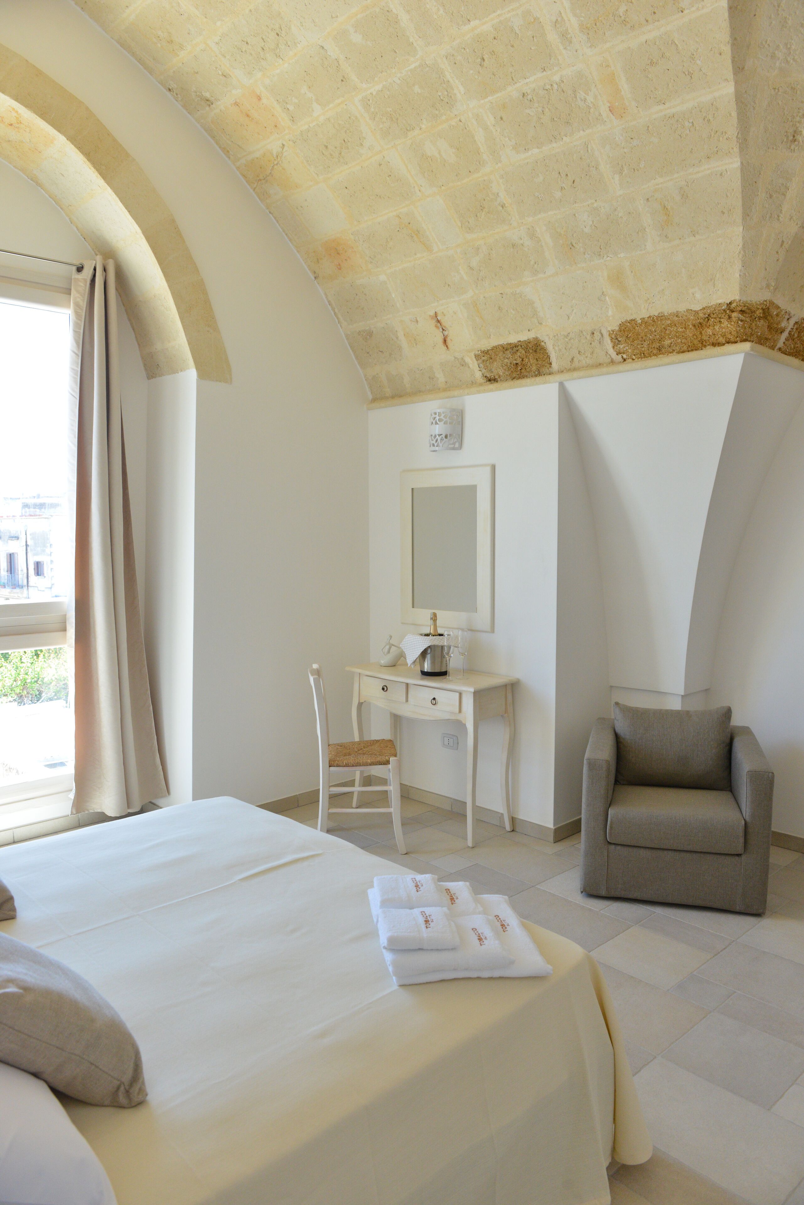 Una habitación de hotel con cama, escritorio, silla y un ventanal grande.
