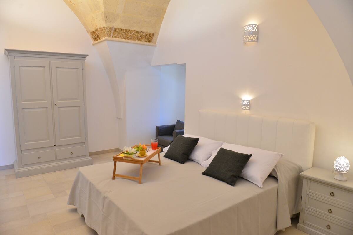 Quarto com cama, mesa de cabeceira, luminária e armário.