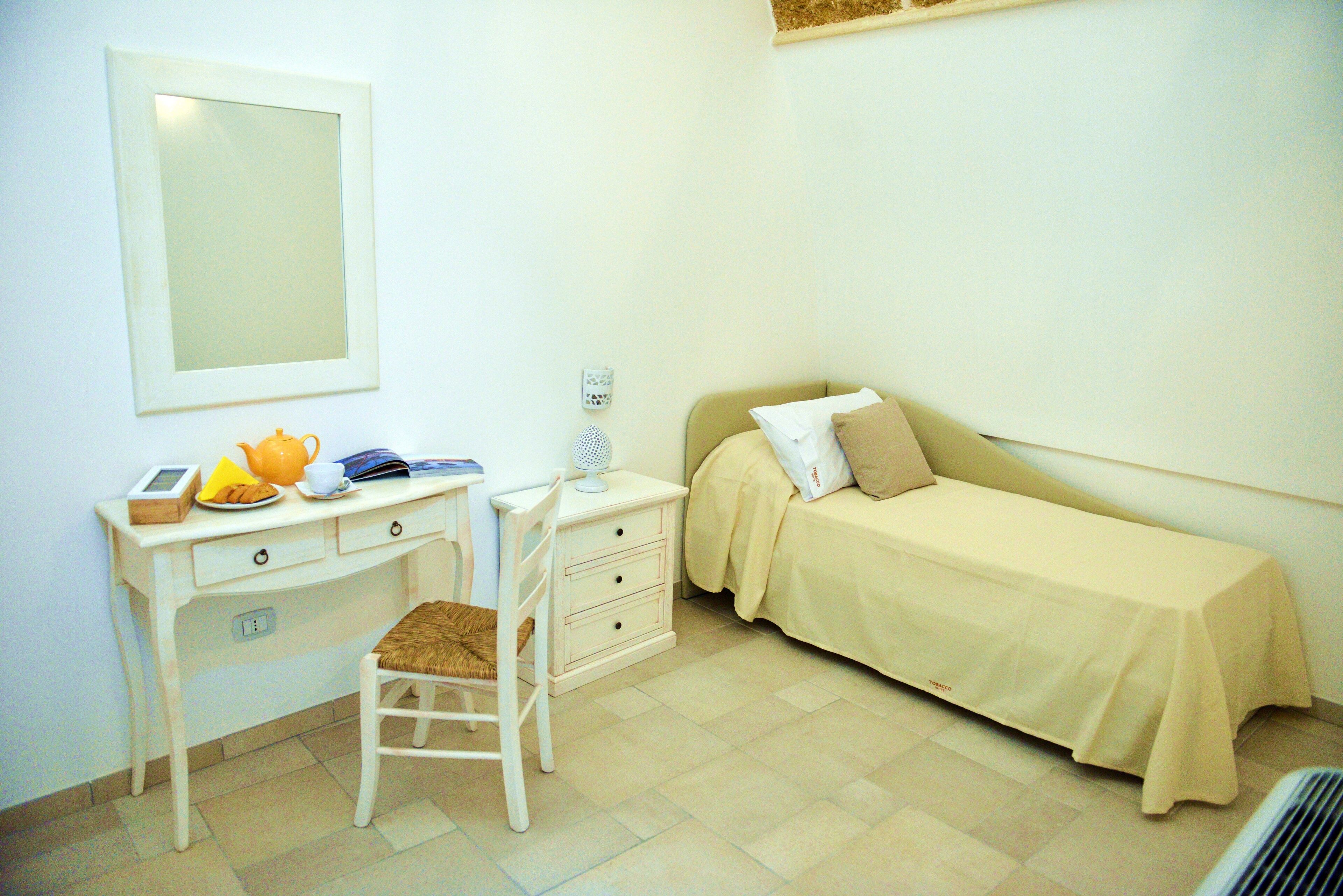 A small, clean room with a desk, chair, and a bed.