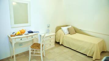 A small, clean room with a desk, chair, and a bed.