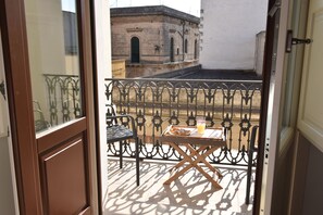 A balcony with a metal railing, a wooden table, and a chair. - Tobacco Suite (Mesagne)