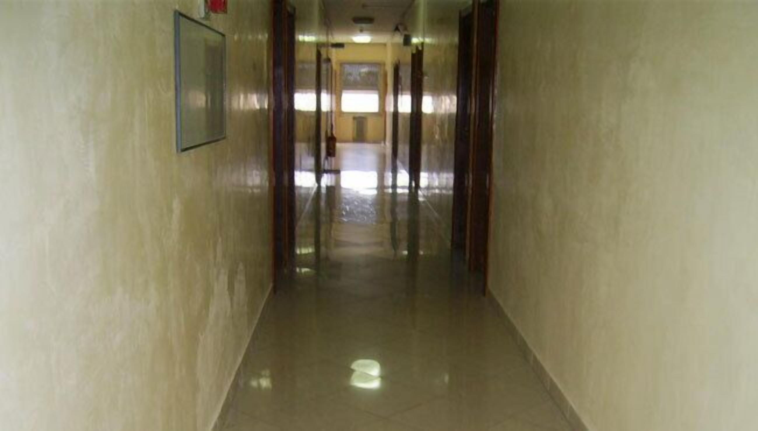 A corridor with a tiled floor and wooden doors.