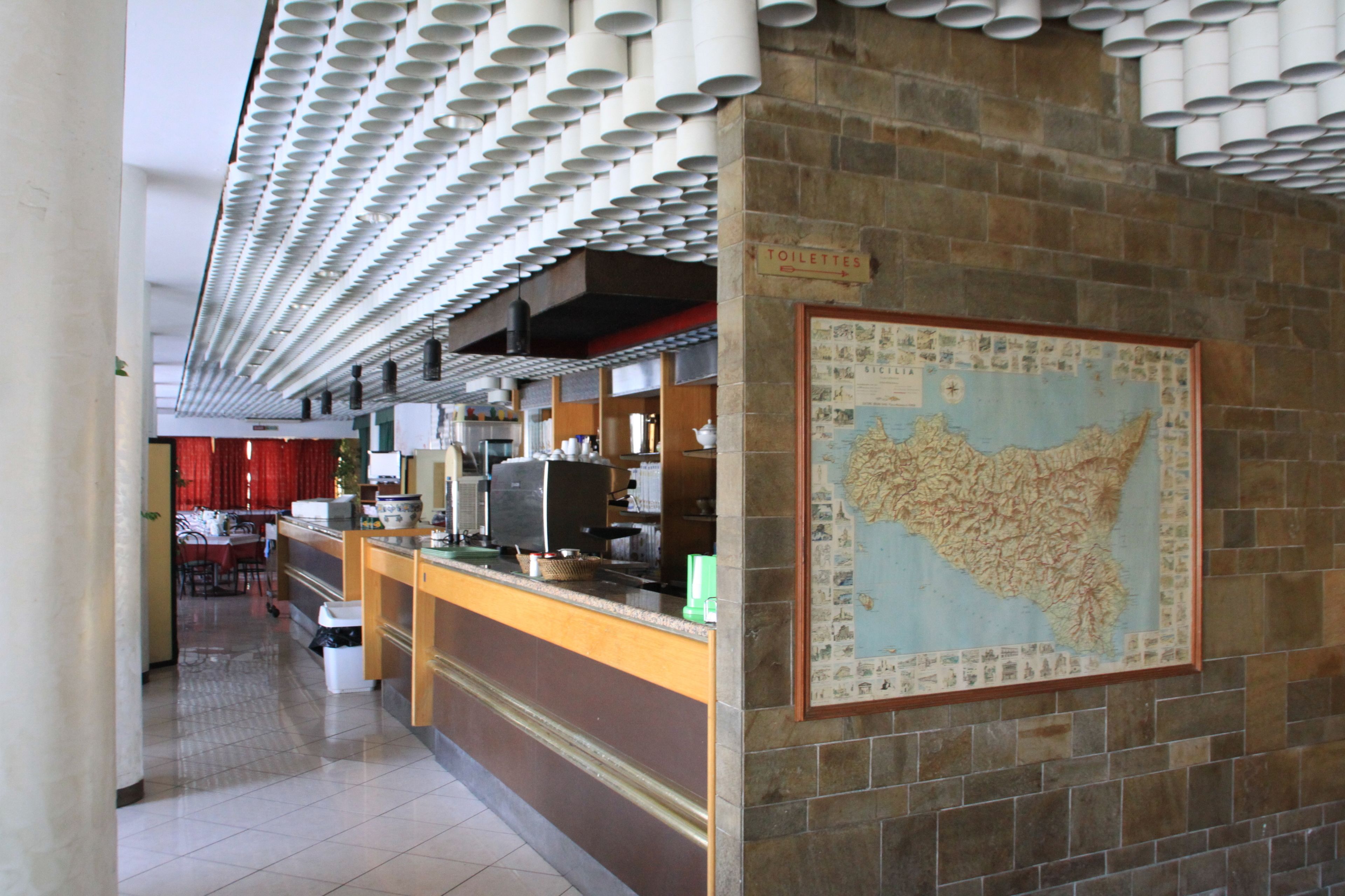 A restaurant with a tiled floor, a counter with a map, and a sign indicating the location of toilets.