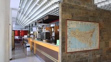 Un restaurant avec un sol carrelé, un comptoir sur lequel est posée une carte, et un panneau indiquant l’emplacement des toilettes.
