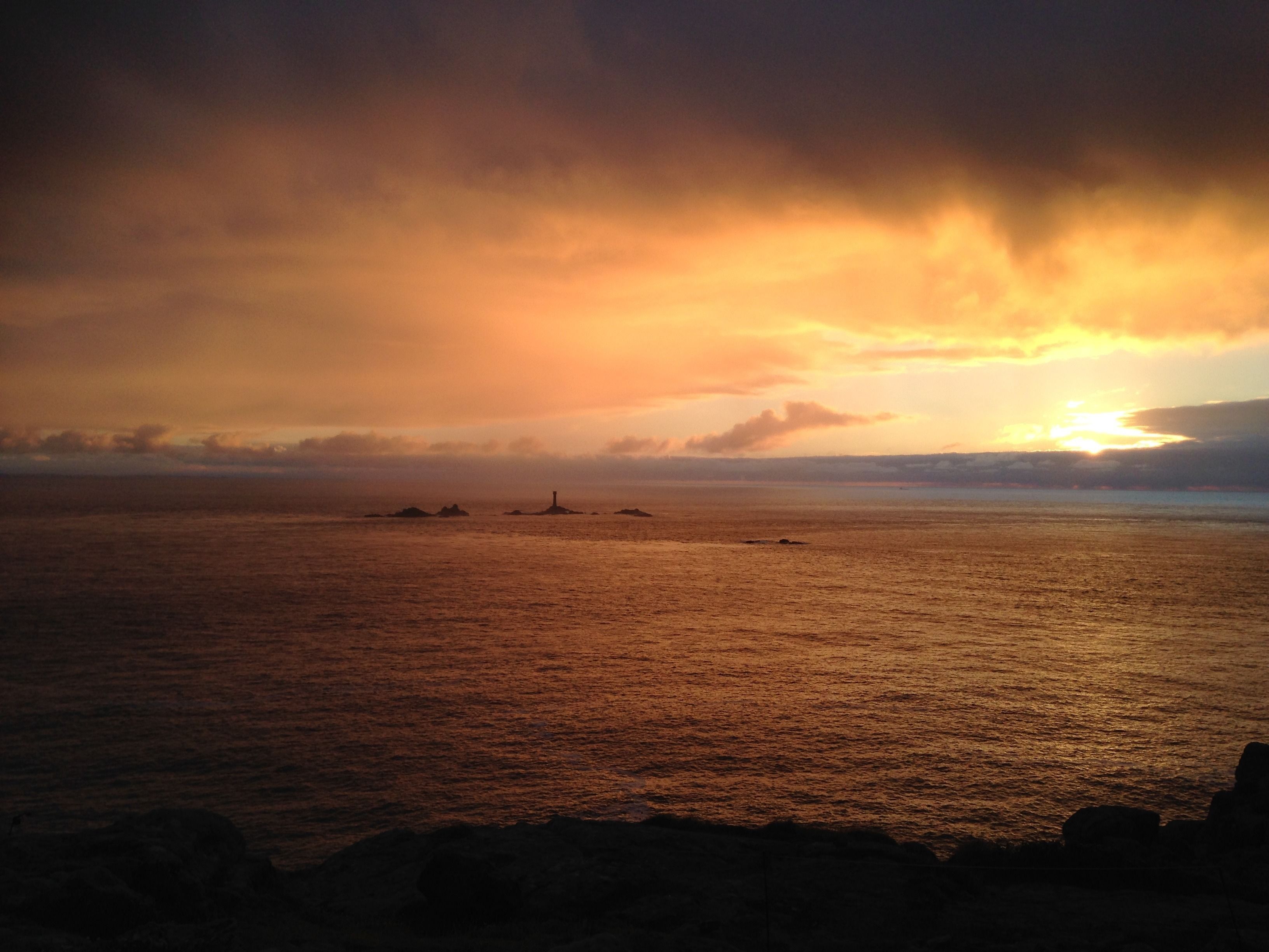 A sunset over a calm sea with distant landmasses.
