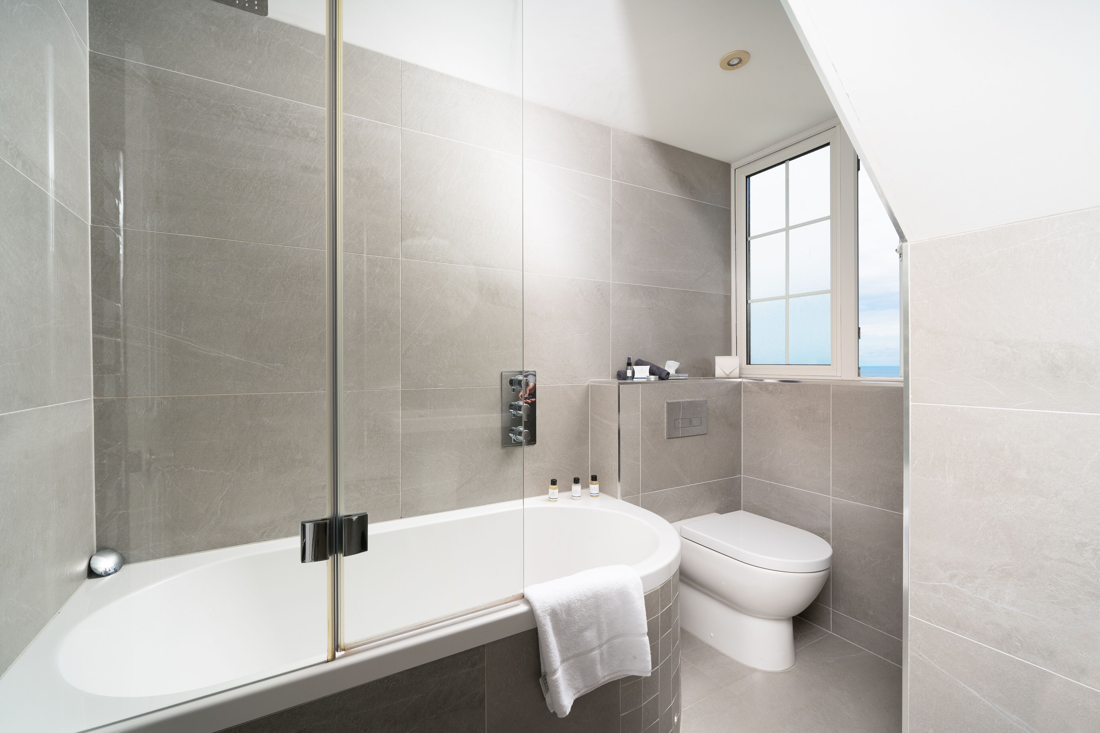 Un baño moderno con ducha acristalada, bañera independiente y retrete.
