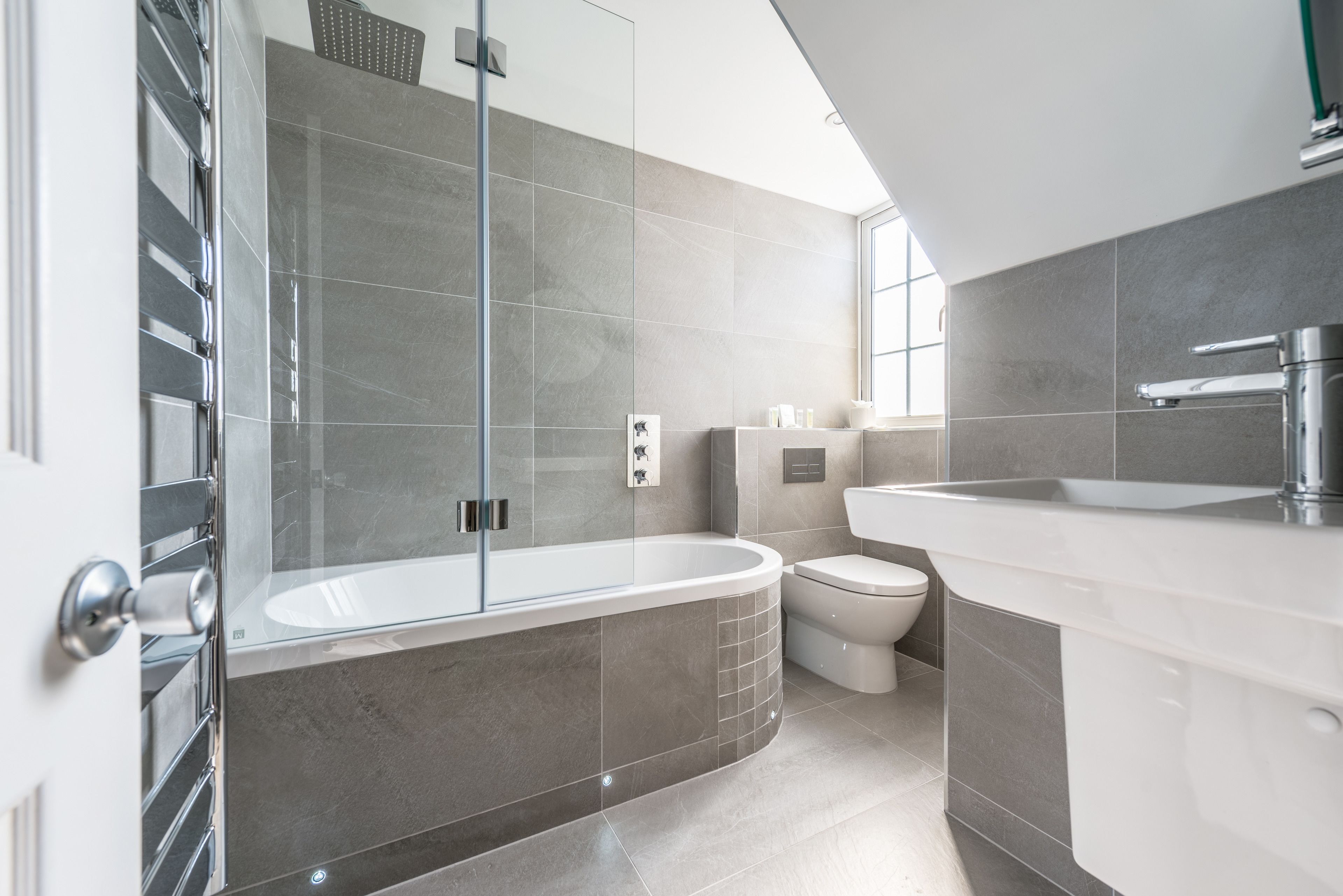 A modern bathroom with a glass-enclosed shower, a freestanding bathtub, a toilet, and a sink.