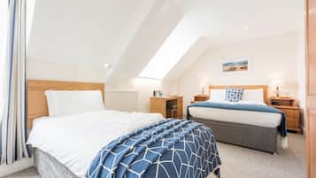 A bedroom with two beds, a wooden headboard, bedside tables, and a painting on the wall.