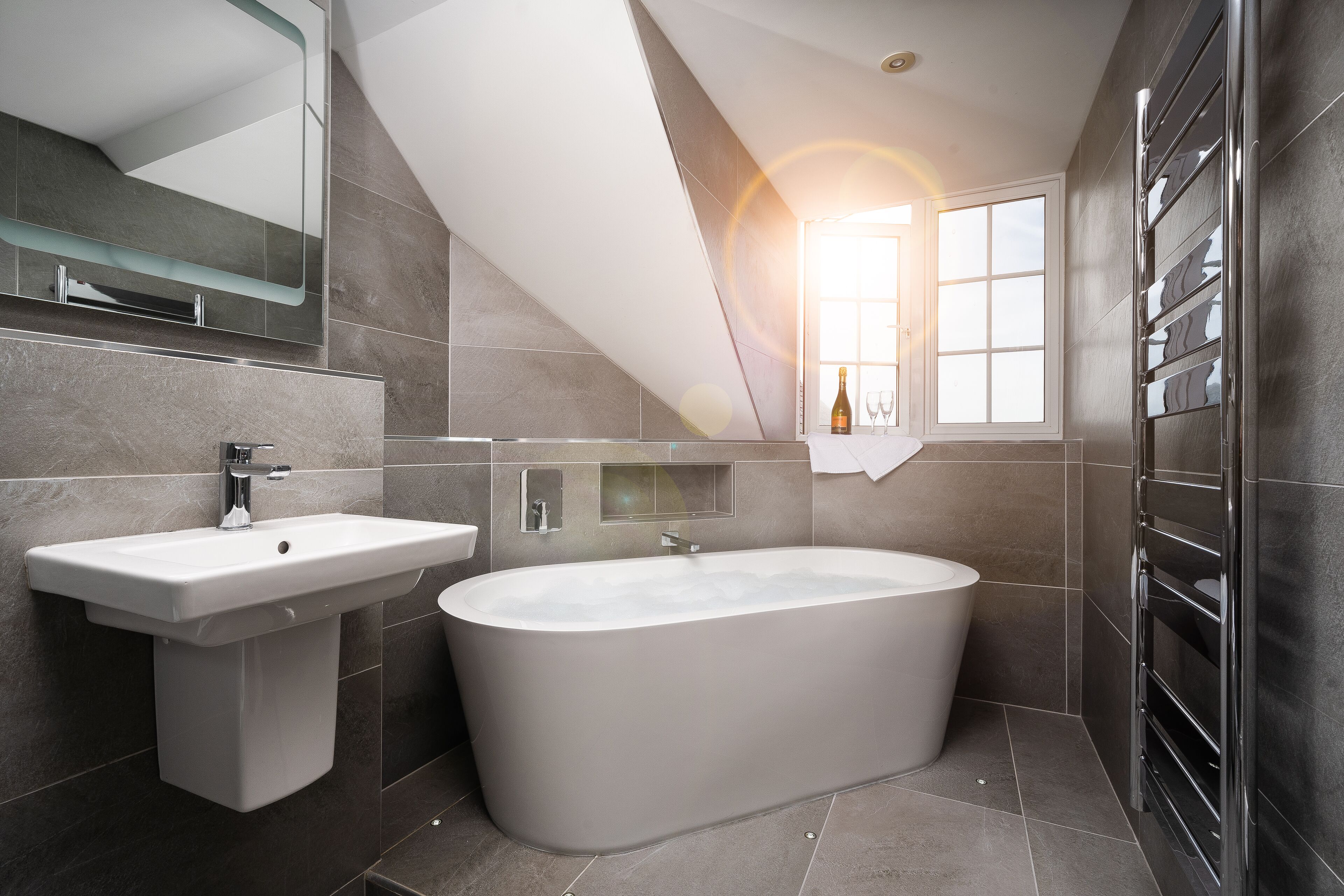 Un baño moderno con una bañera independiente, un lavabo sobre pedestal y una zona de ducha con mampara de cristal.