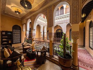 A spacious interior with high arches, ornate columns, and a cozy seating area with a coffee table and cushions.