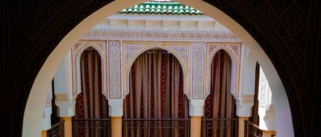 An arched doorway with intricate patterns and a view of a courtyard with a green tiled floor.