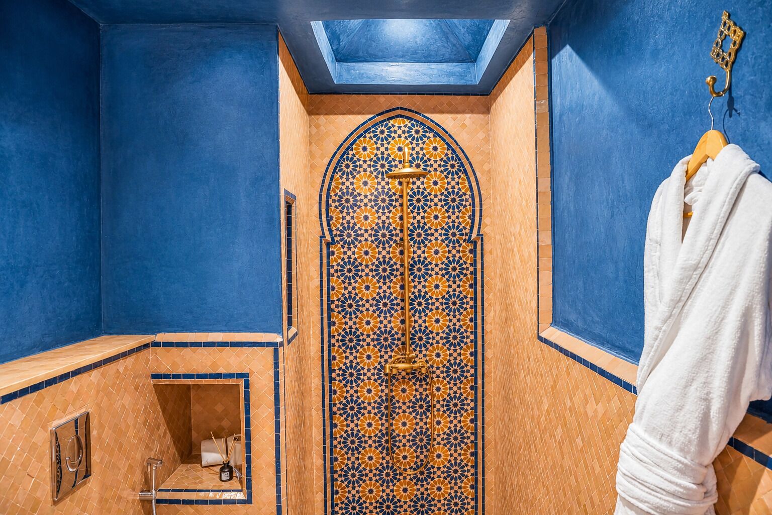 A bathroom with blue walls, a patterned tile shower, and a towel rack.