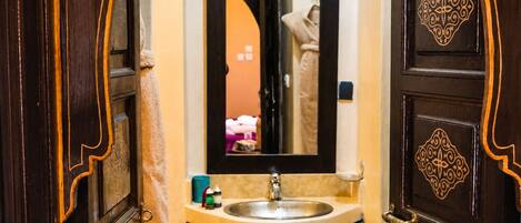 A bathroom with a sink, mirror, and ornate wooden doors.