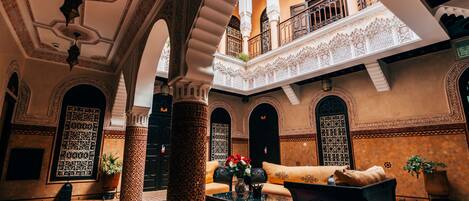 A spacious interior with a central seating area, ornate columns, and a decorative ceiling.