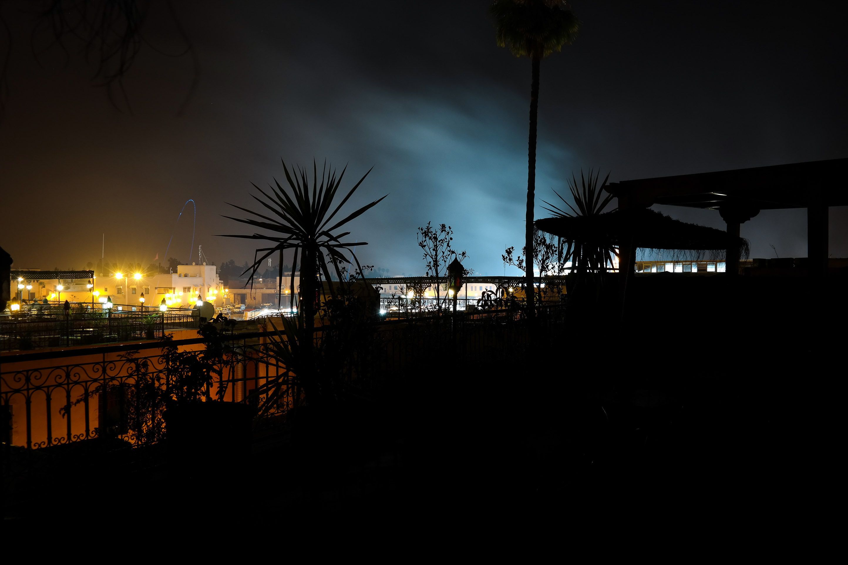 A nighttime view of a cityscape with illuminated buildings and a bridge.