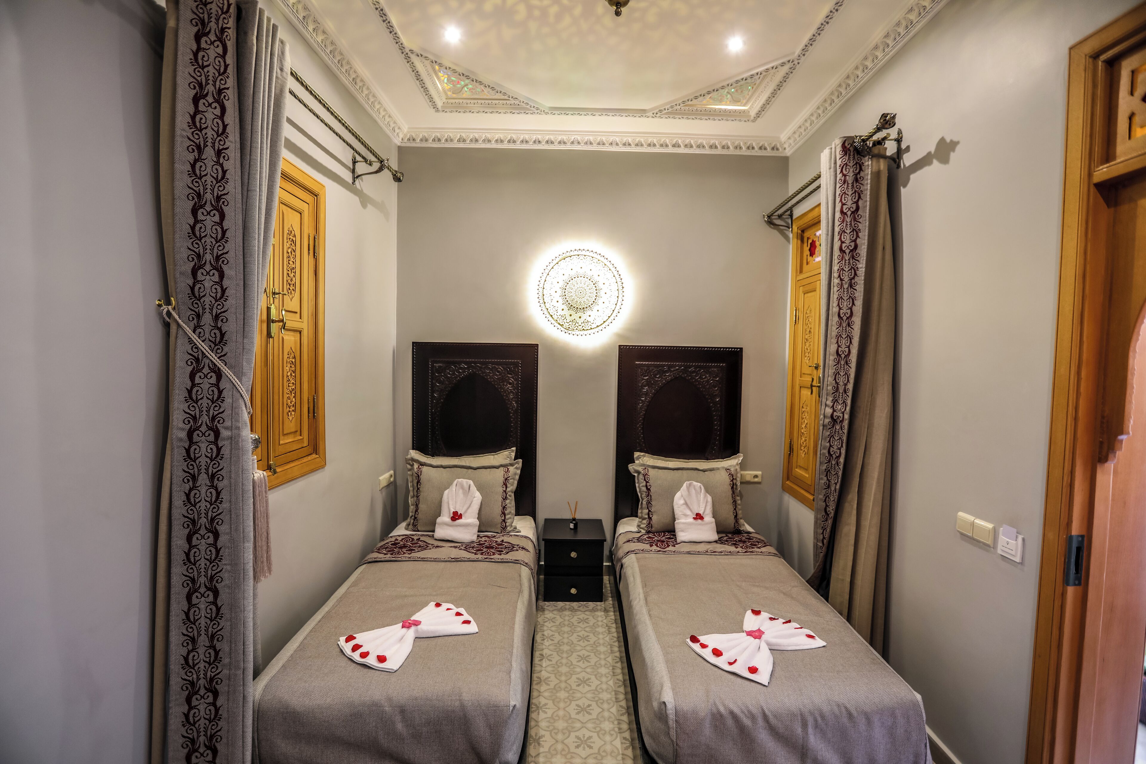 Une chambre d’hôtel avec deux lits, un lustre et une porte en bois.