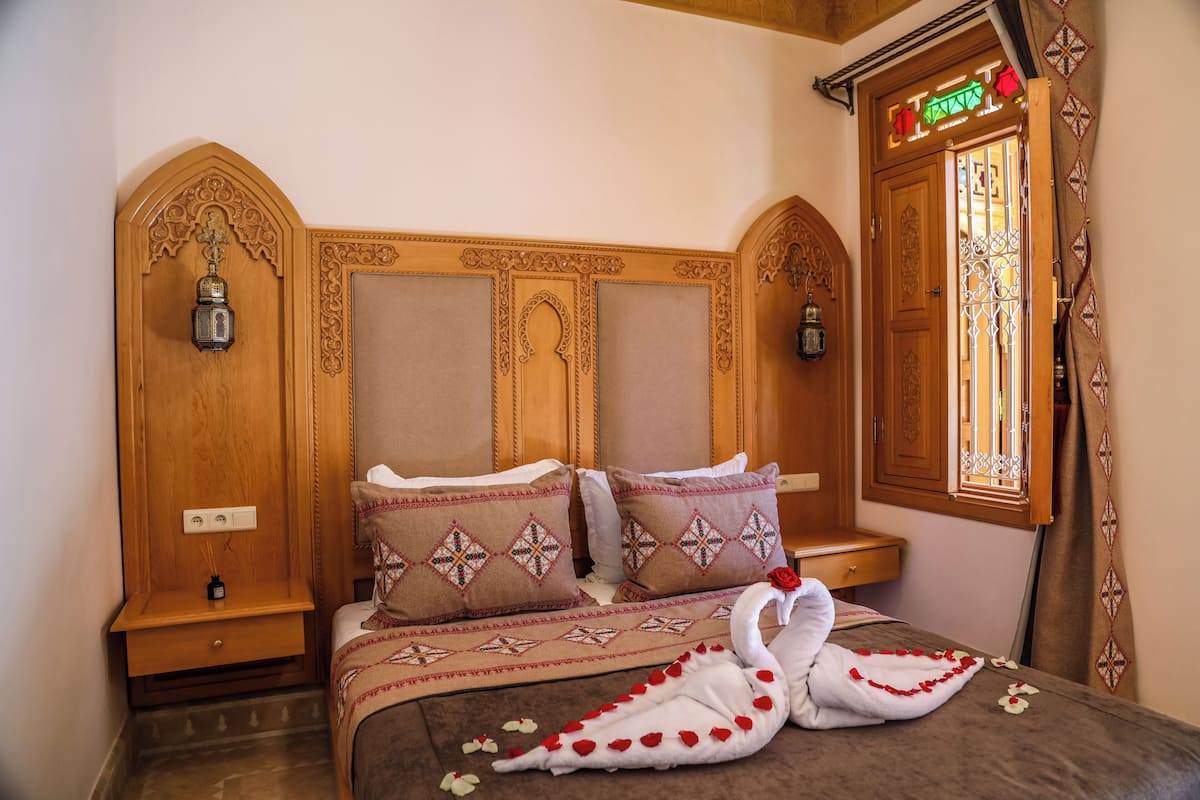 A bedroom with a wooden headboard, two bedside tables, a bed with patterned bedding, and a decorative swan.