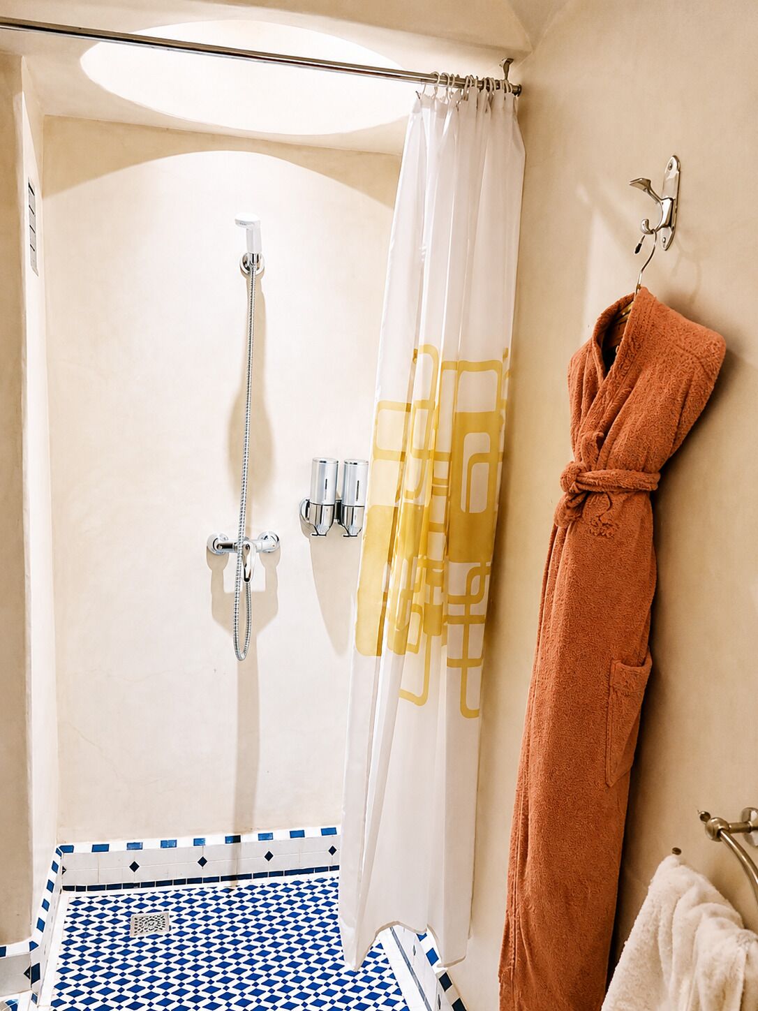 A bathroom with a shower, a towel rack, and a patterned floor.