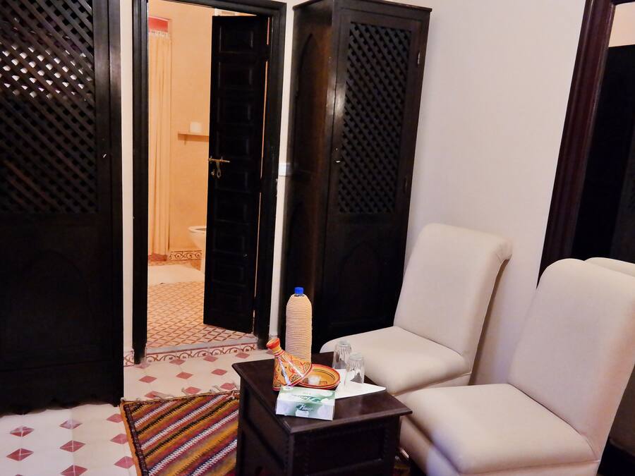 A living room with a sofa, a small table with a bottle and a tissue box, and a patterned rug.
