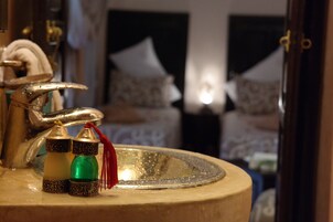 Un baño con lavamanos, espejo y cama con almohadas.