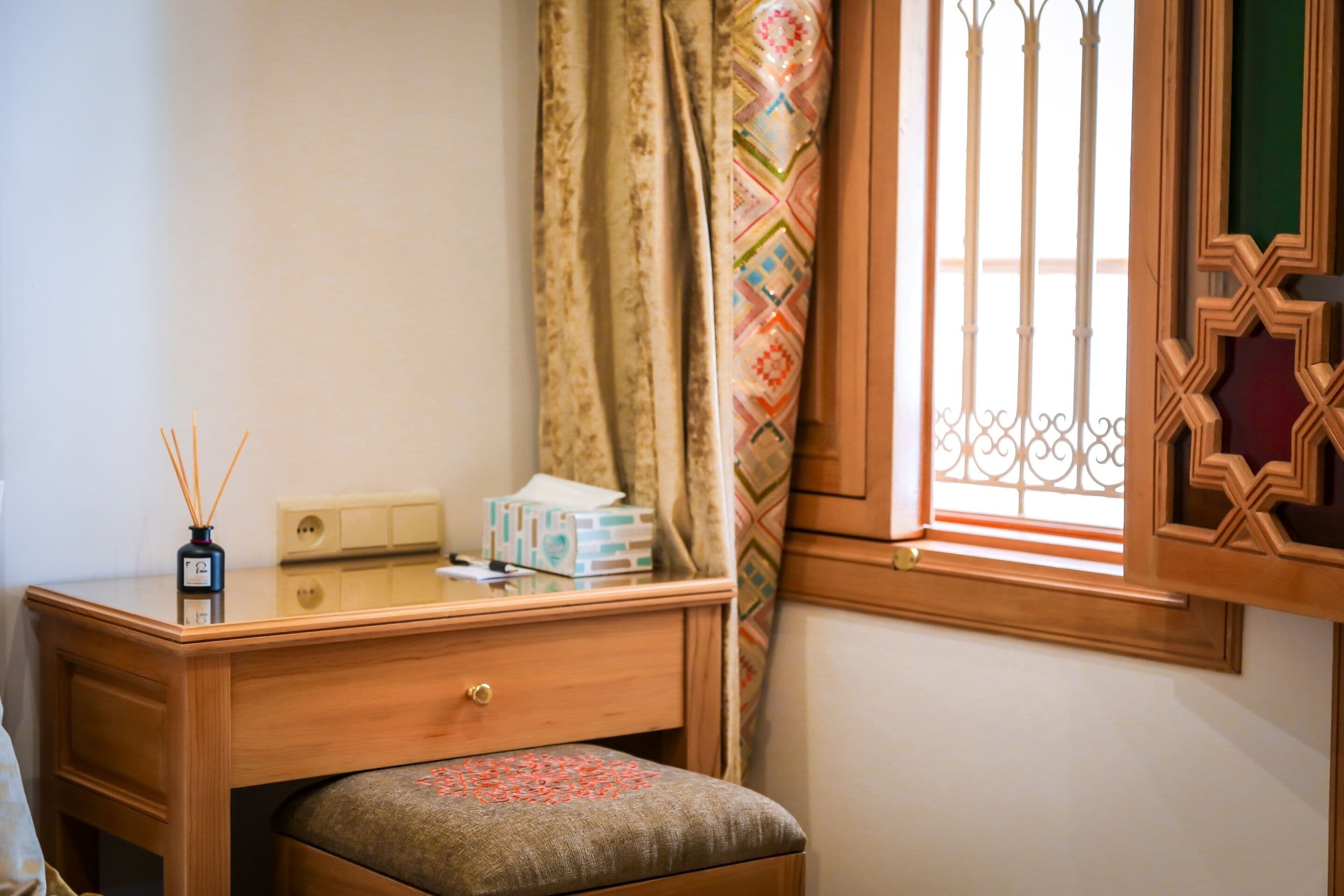A wooden desk with a drawer, a small table, and a box of tissues.