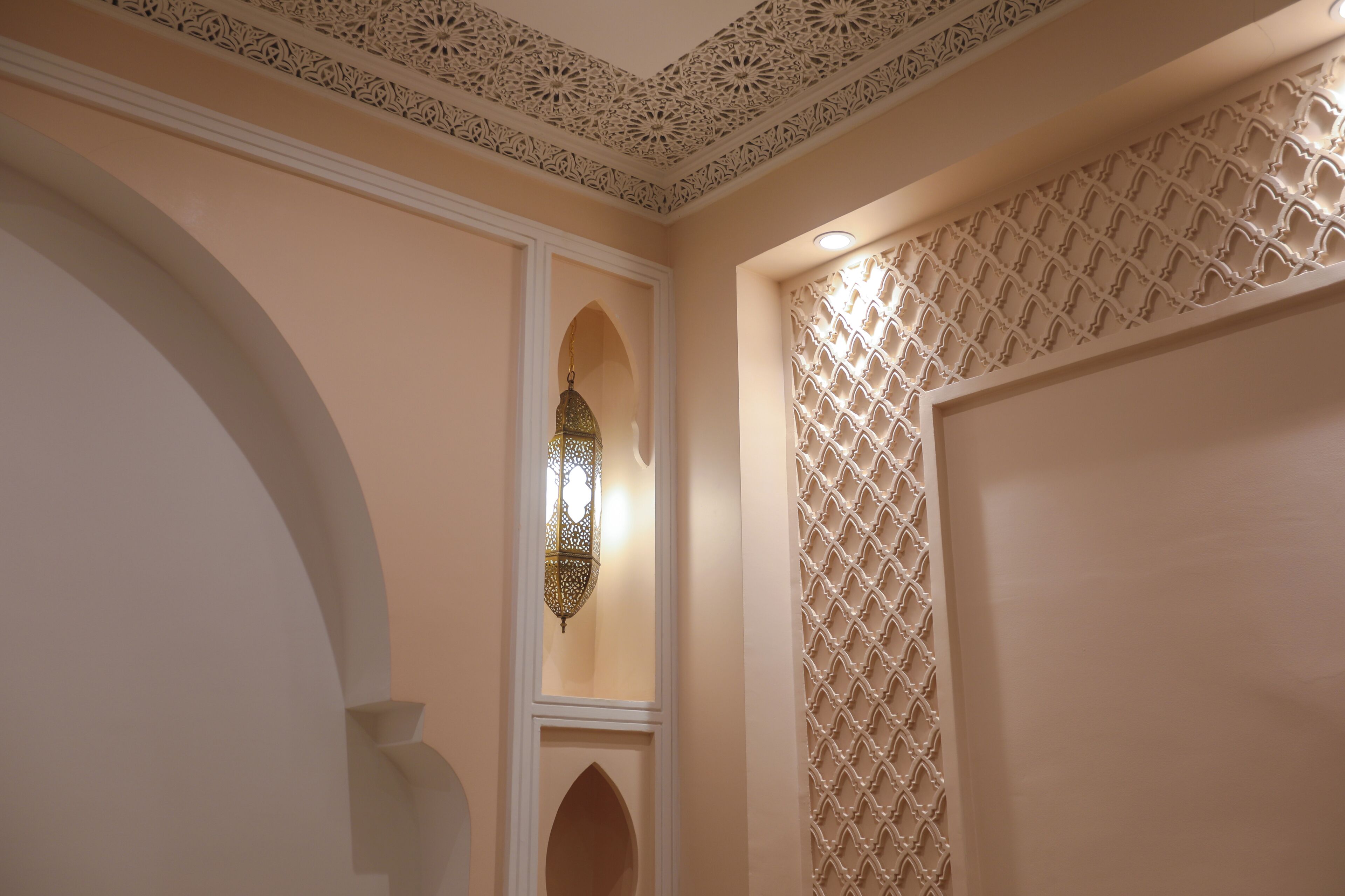 A room with a decorative ceiling, a hanging lantern, and a lattice-patterned wall.