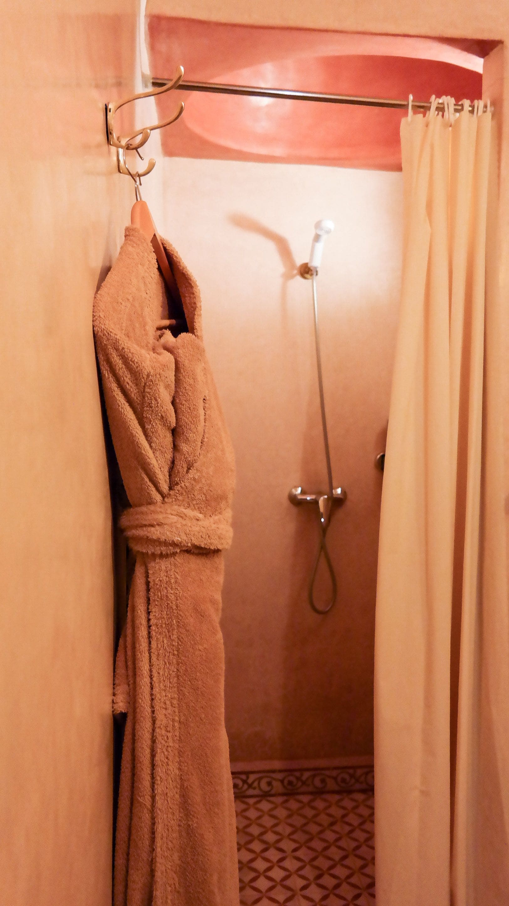 A bathroom with a shower, a towel rack, and a curtain.