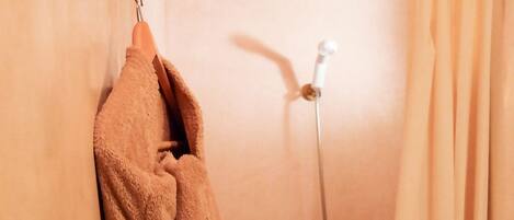 A bathroom with a shower, a towel rack, and a curtain.