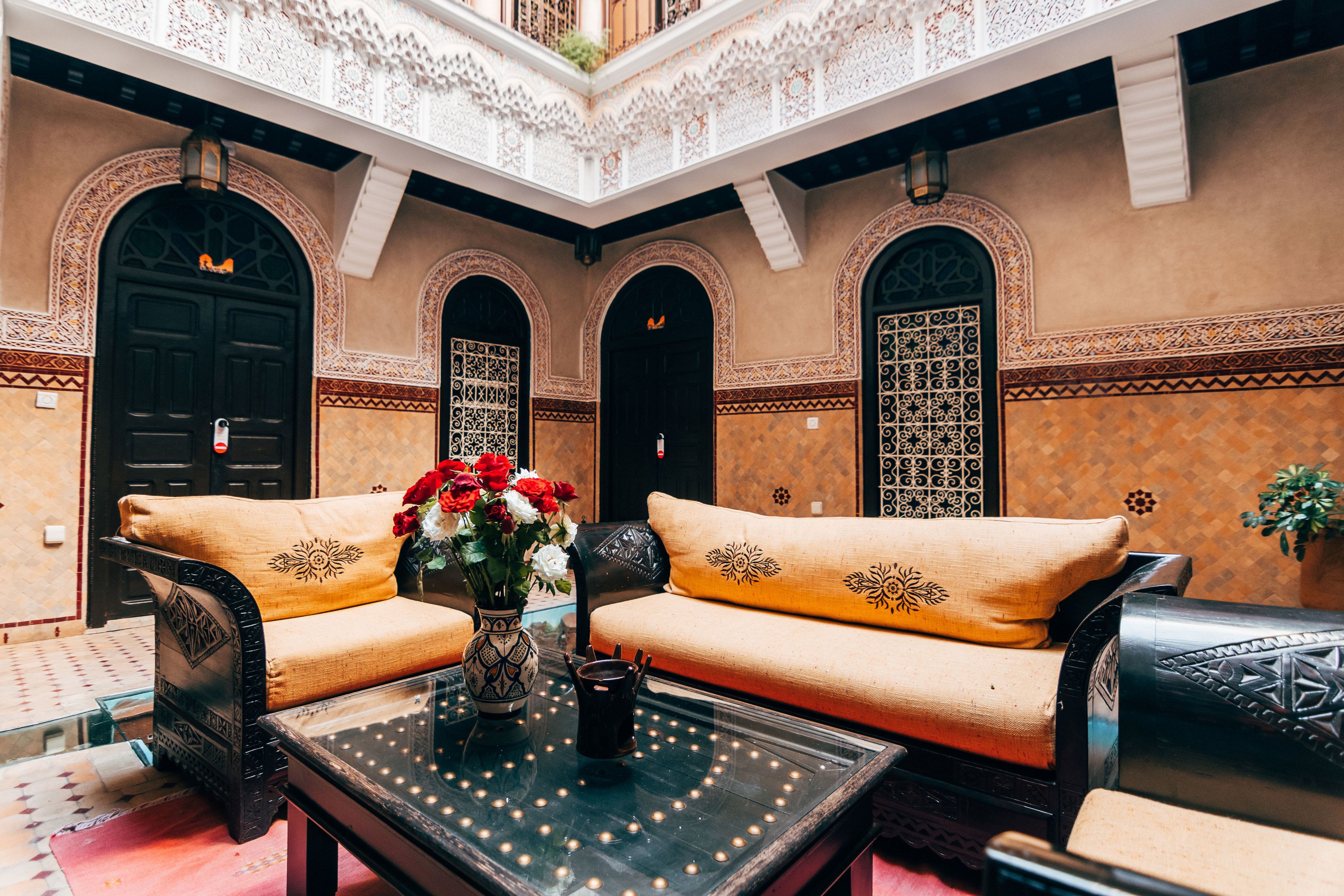 Un interno marocchino con un divano, un tavolo con un vaso di fiori e archi decorativi.