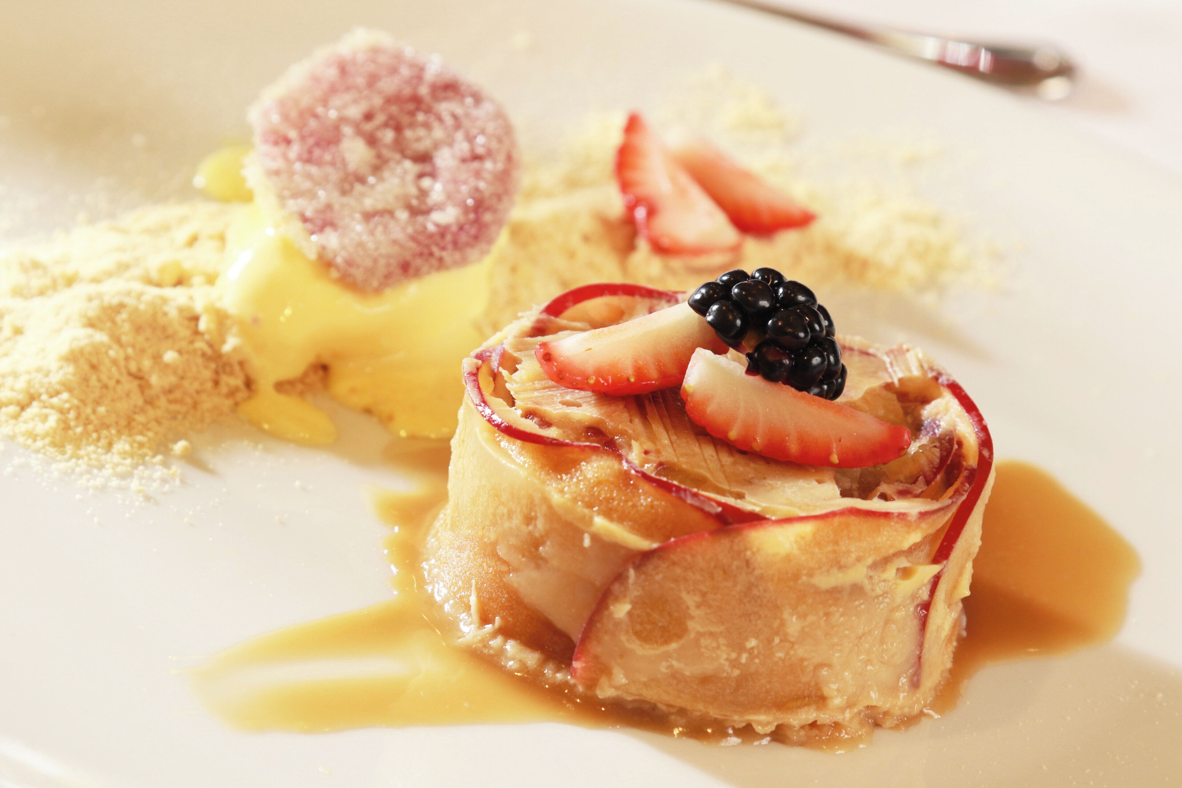 A dessert plate with a layered cake, fruit slices, and a scoop of ice cream.
