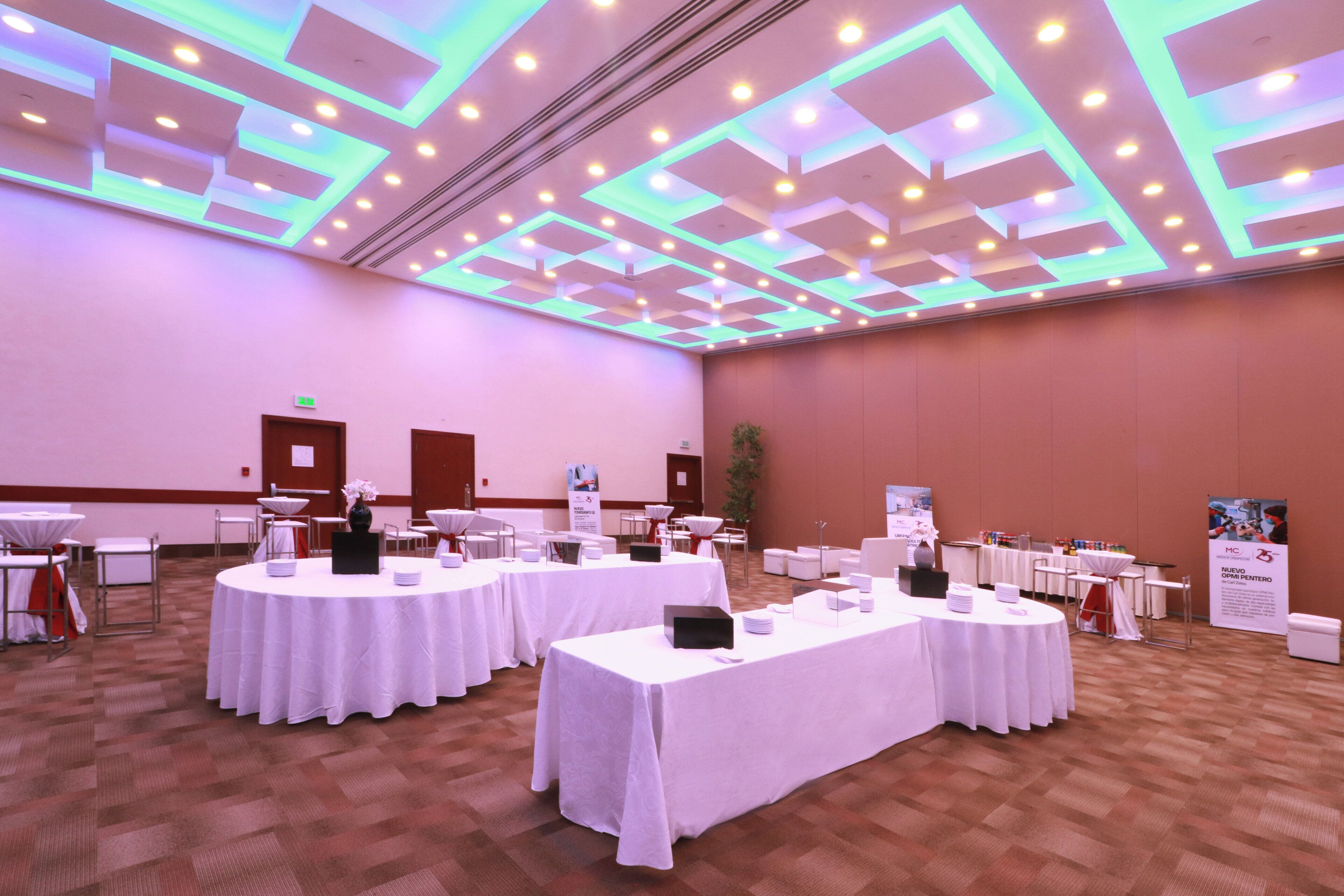 A conference room with round tables, white tablecloths, and a modern ceiling design.